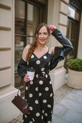 a lady in a black dress with polka dots and a black leather coat